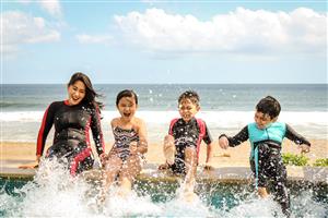 Smiling Woman And Children Splashing Their Feet In The Pool